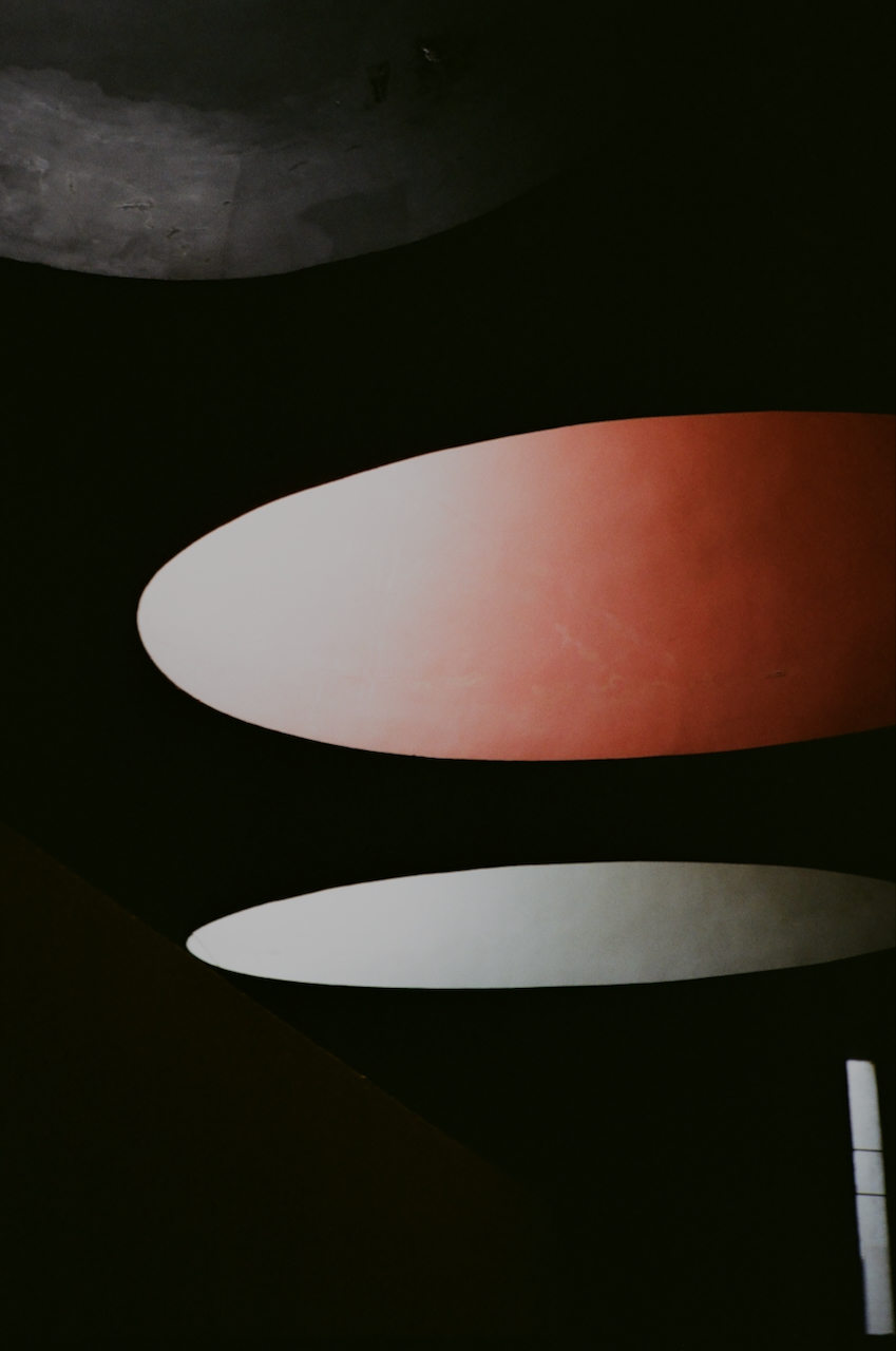 A collection of surfboards, with three visible in the foreground, and a dark background that suggests an indoor setting
