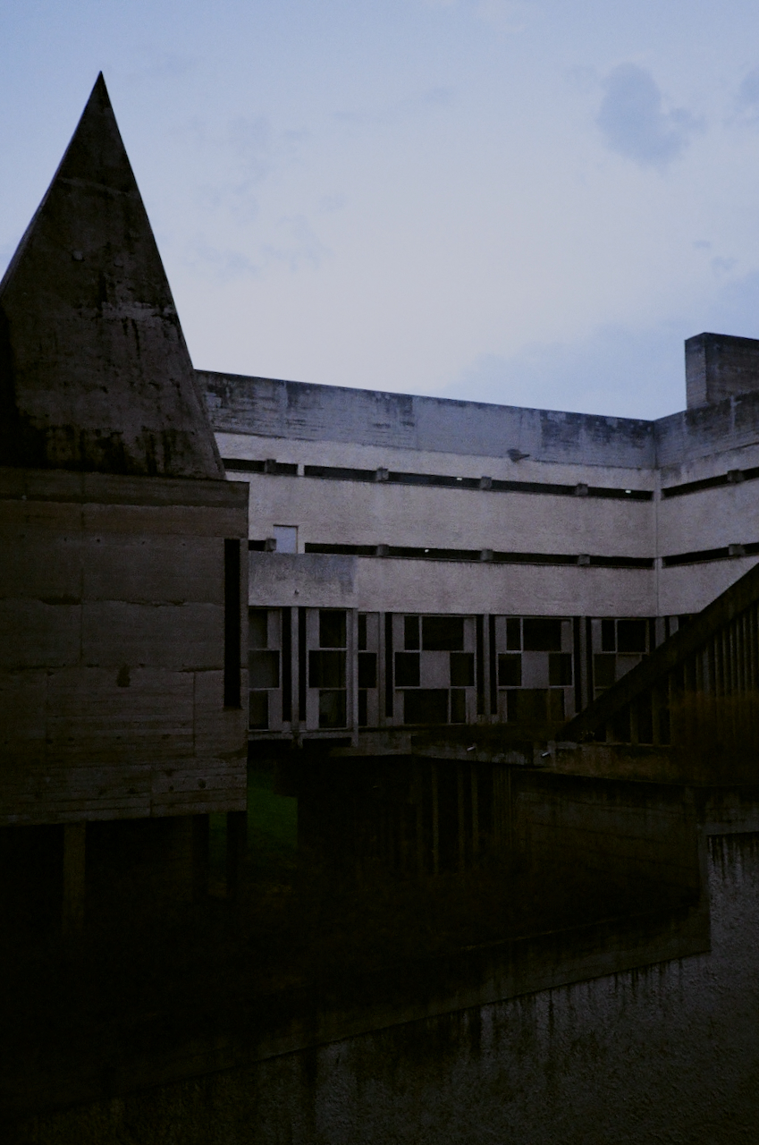 A large, modern building with a geometric design, captured in a low-light, nighttime setting