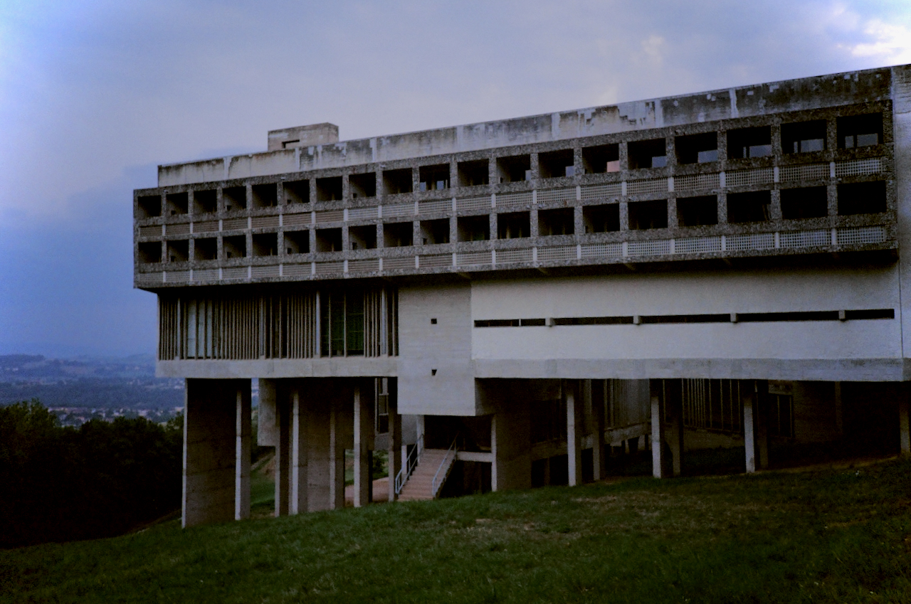 A large, abandoned two-story building with multiple windows and a flat roof