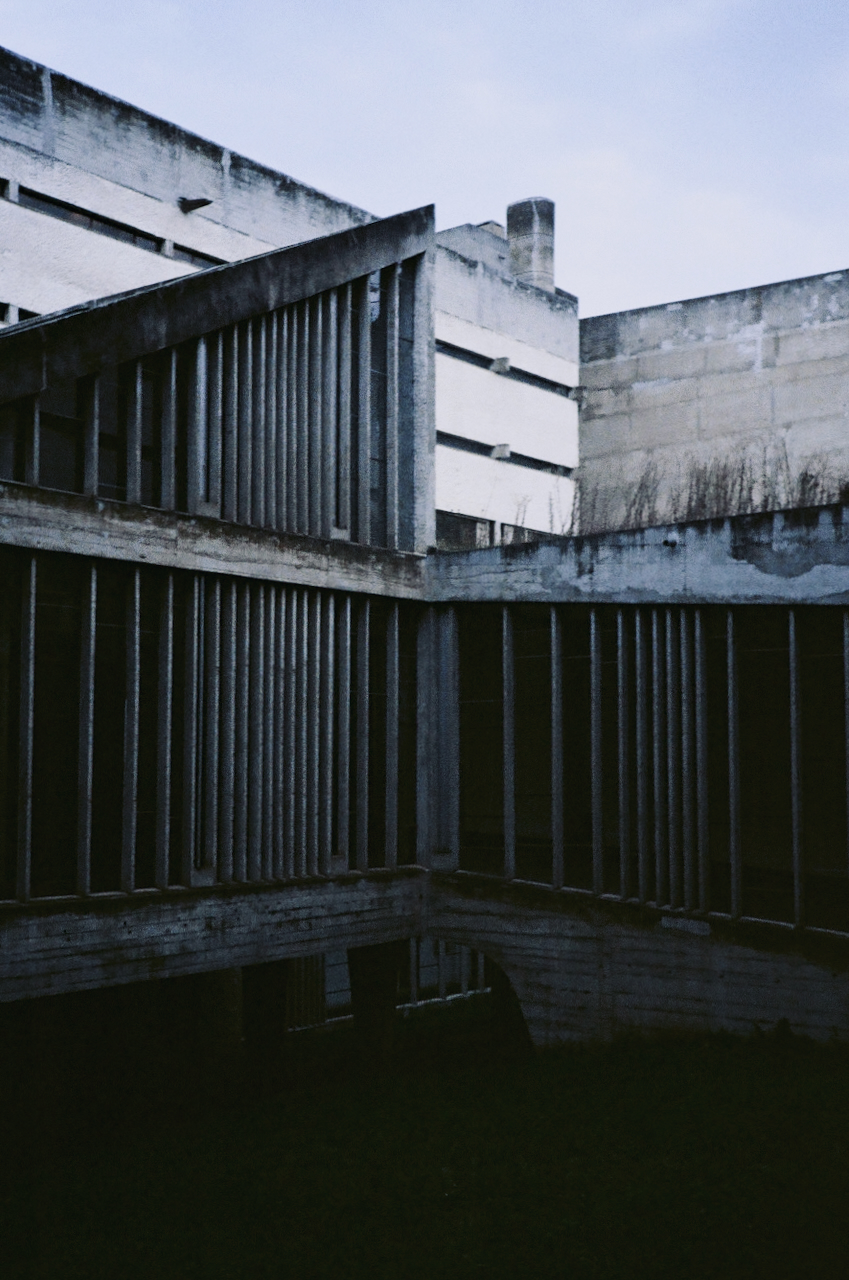 Abandoned building with multiple windows and a large, open space in the foreground