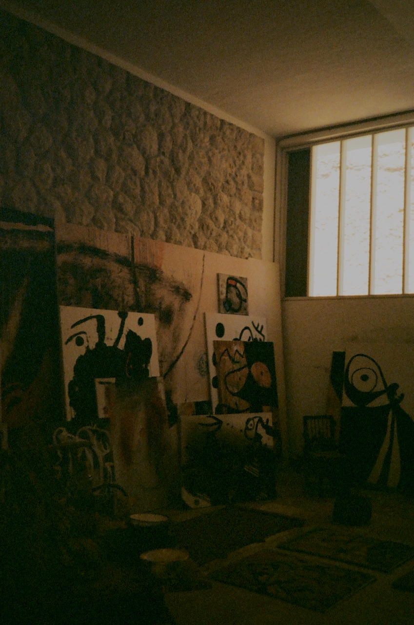 A room with a brick wall, displaying various pieces of art