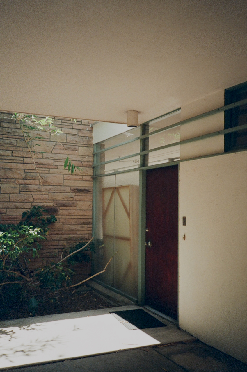 A modern building entrance with a glass door and a brick wall