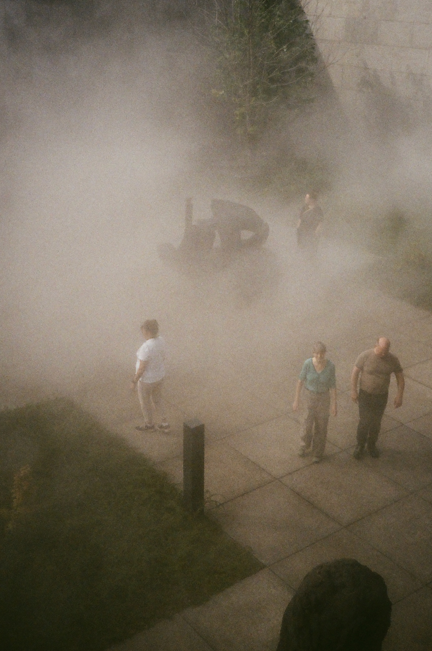 People standing in a foggy area, with a truck in the background