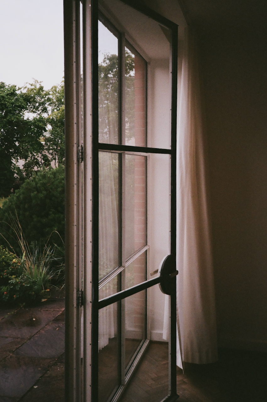 Open window with curtains, overlooking a garden
