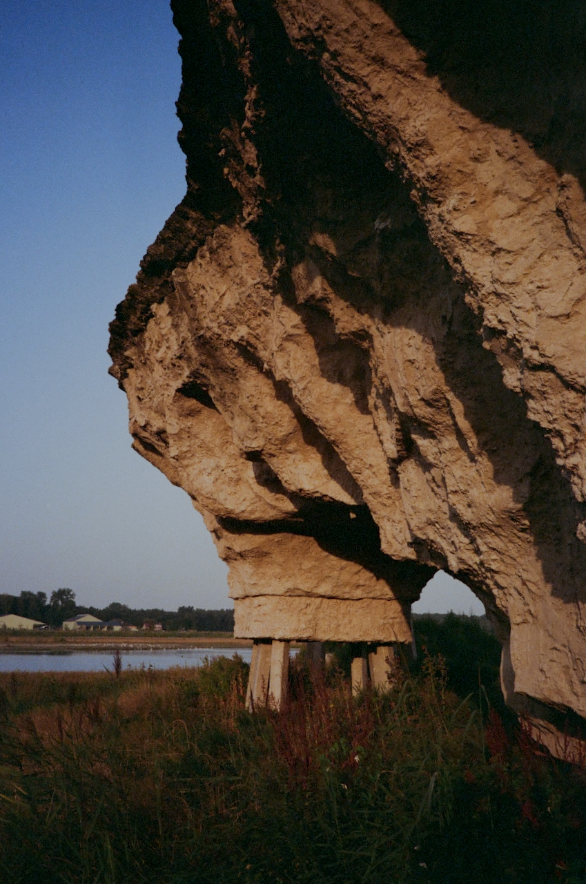 A large rock formation with a cave-like opening, set against a clear sky