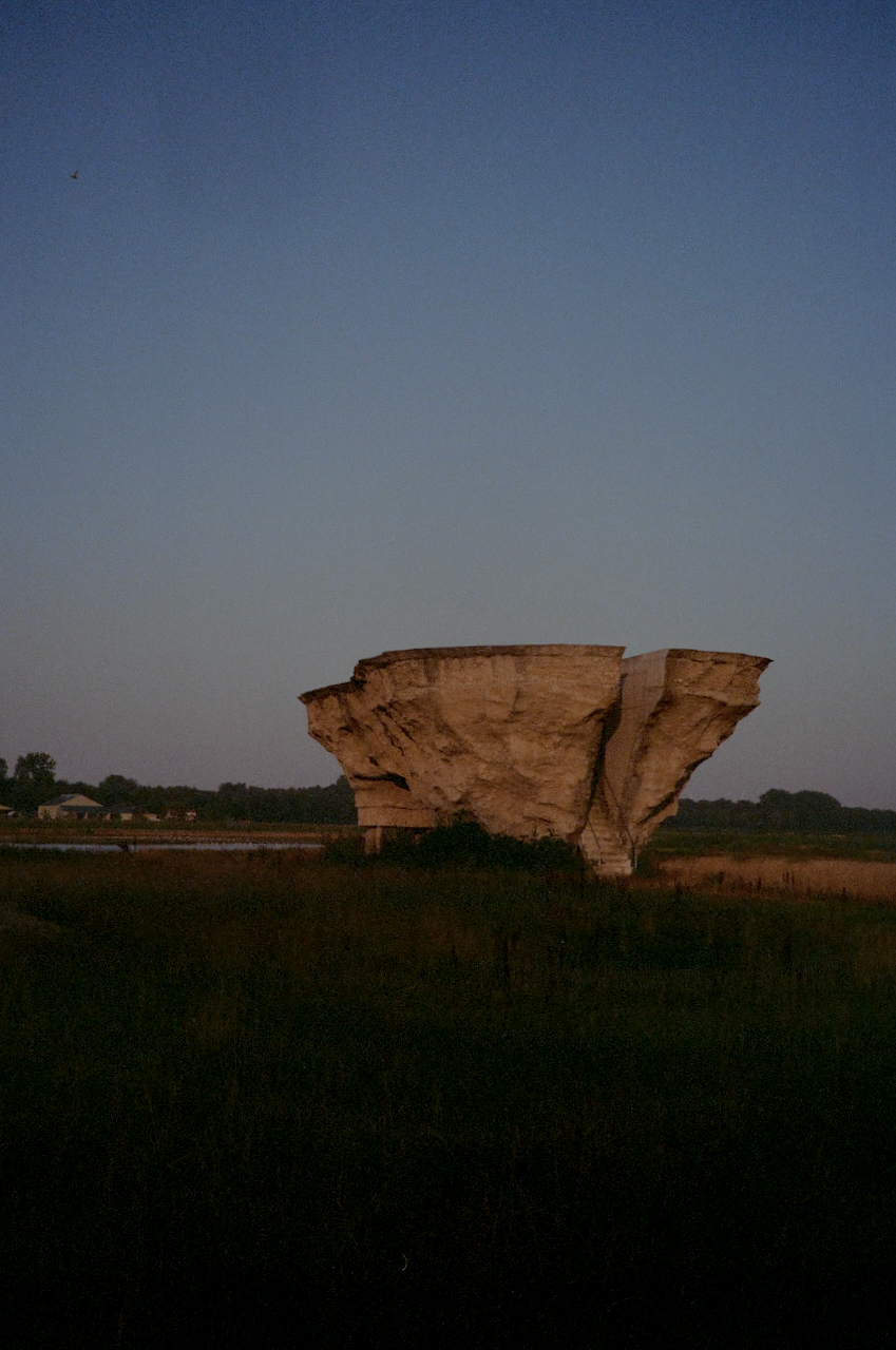 A large rock formation in a field at dusk