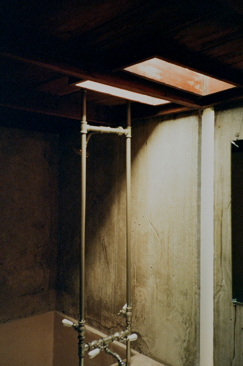 A dimly lit bathroom with a shower area, a toilet, and a sink