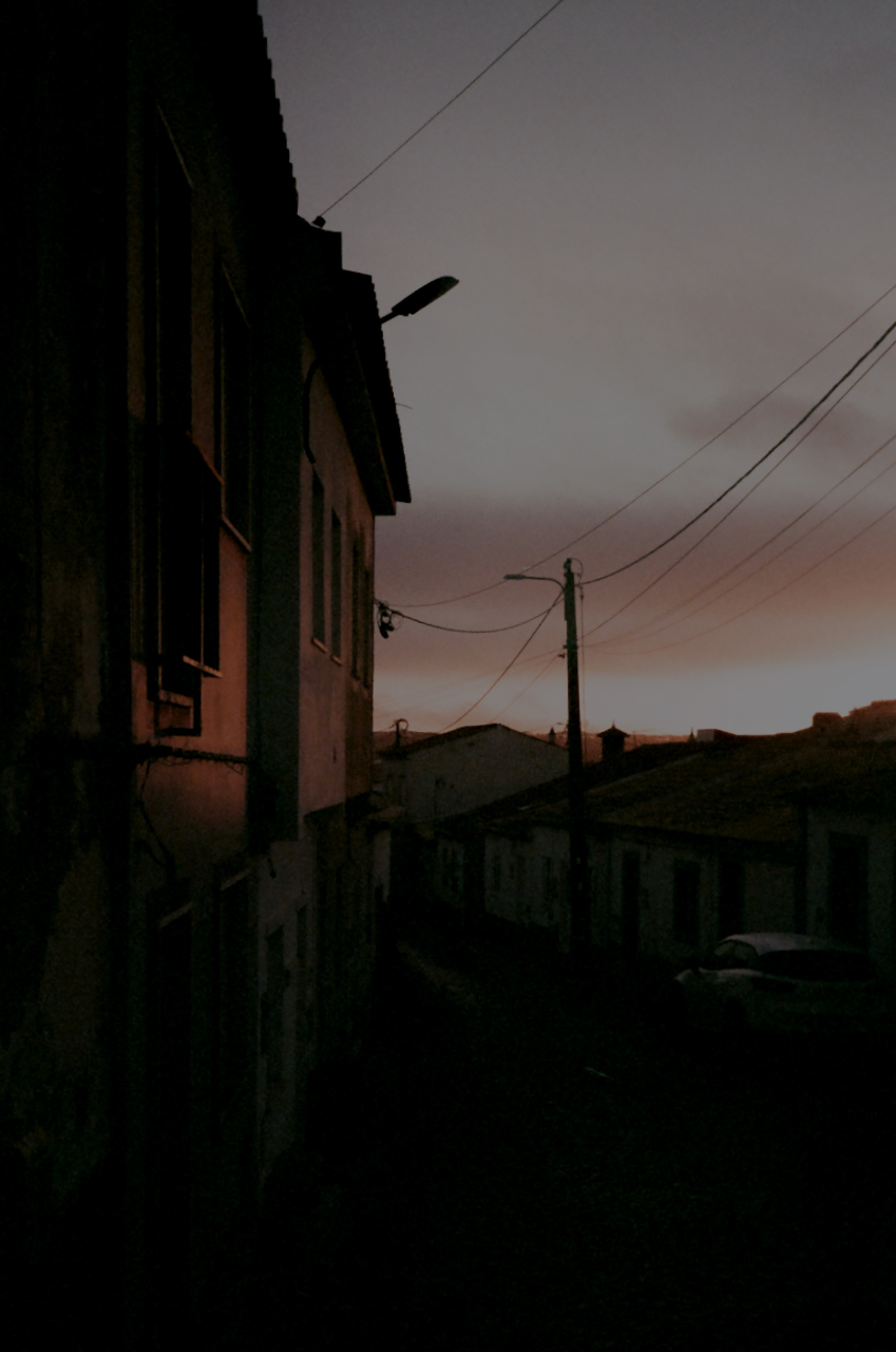 A dark sky at dusk with a silhouette of a building and a telephone pole