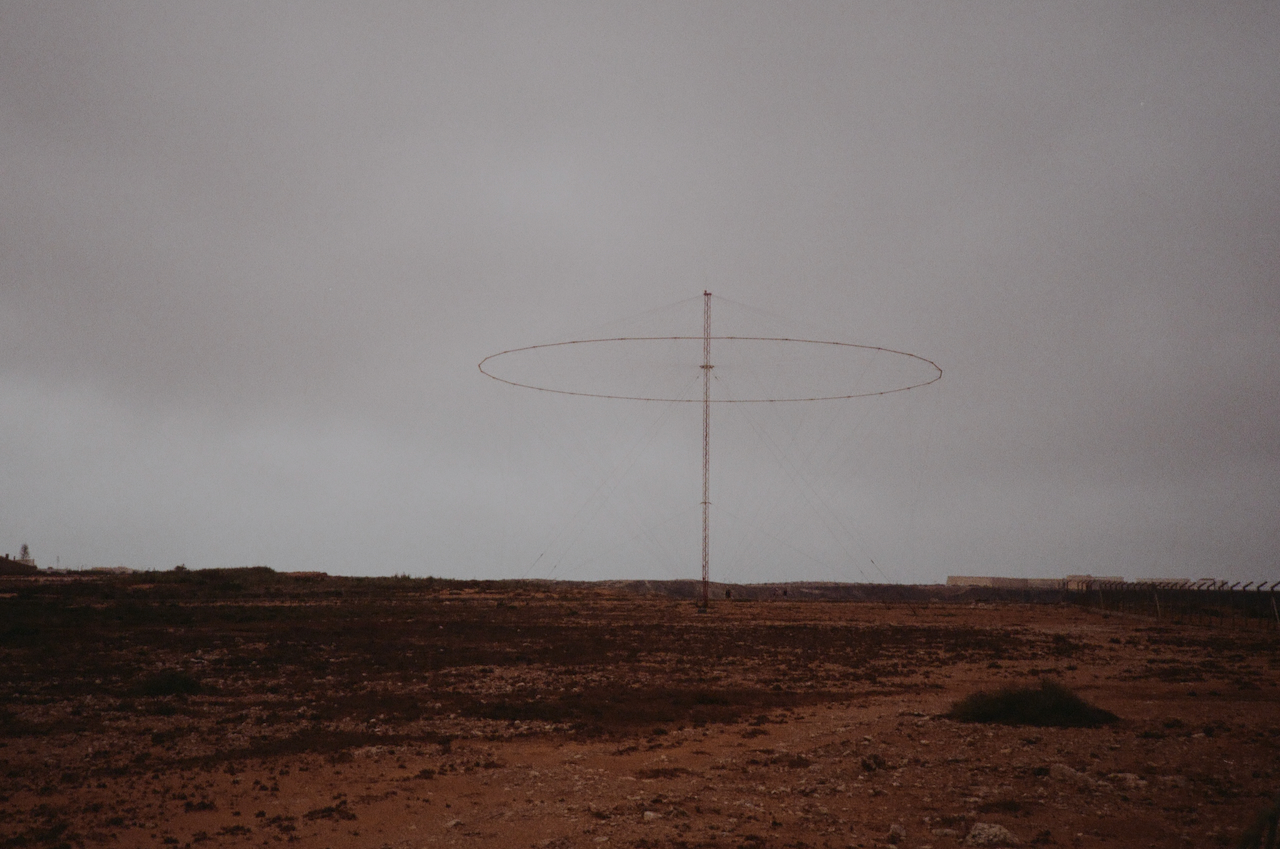 A large antenna stands alone in a barren landscape under a cloudy sky