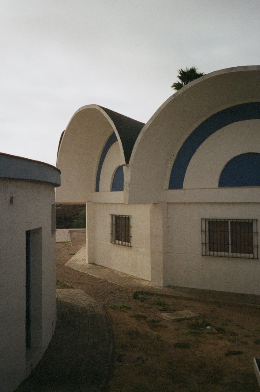 Graph of a building with a curved roof, featuring two arches, set against a clear sky