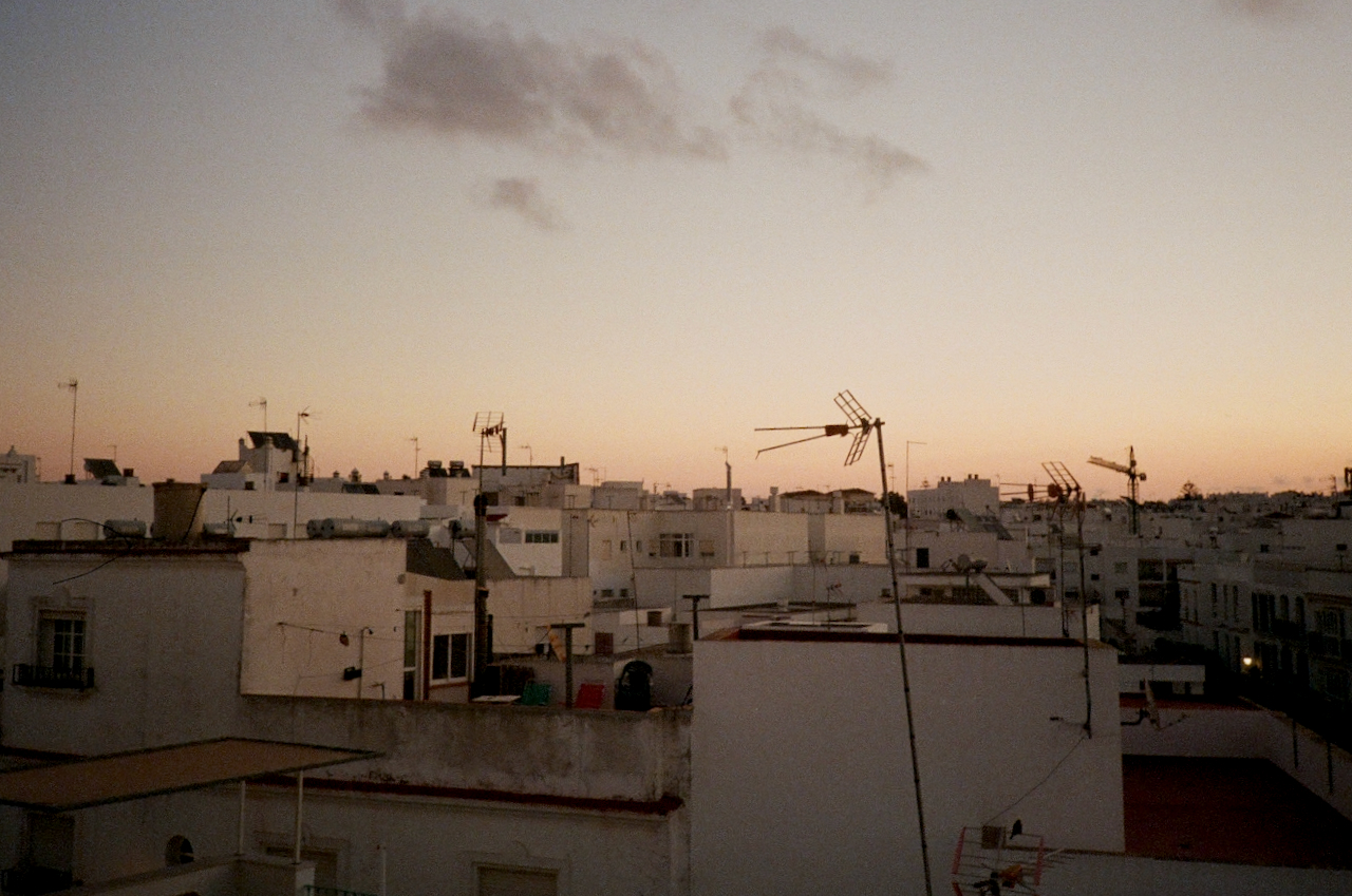A cityscape at dusk with a pinkish sky, buildings, and a clear view of the horizon