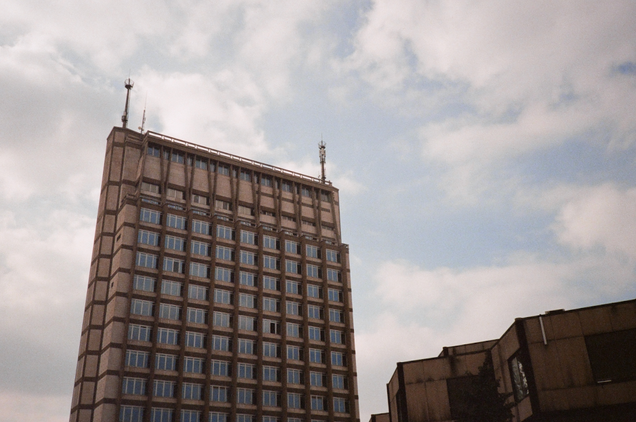 Tall building with many windows, set against a cloudy sky