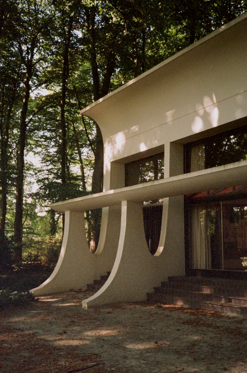 A modern building with a curved roof, surrounded by trees, during the day