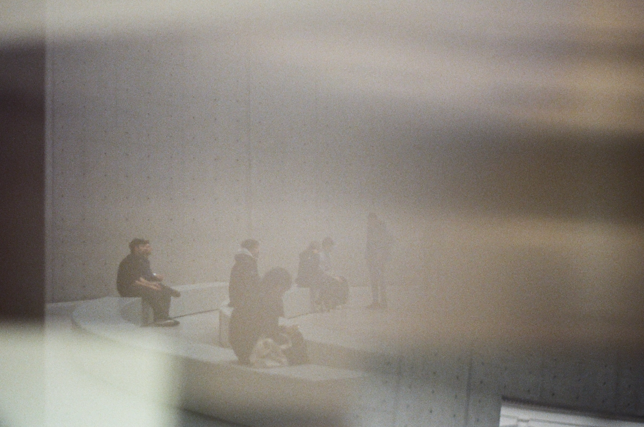 A blurry image of a waiting area with people seated, viewed through a fish-eye lens