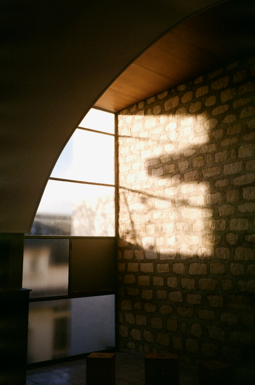 A brick wall with a window, casting a shadow on the wall