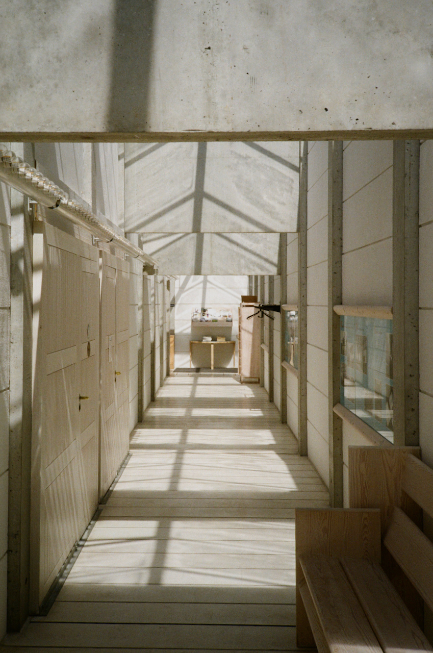Long, narrow hallway with high ceiling, sunlight streaming in, and white walls