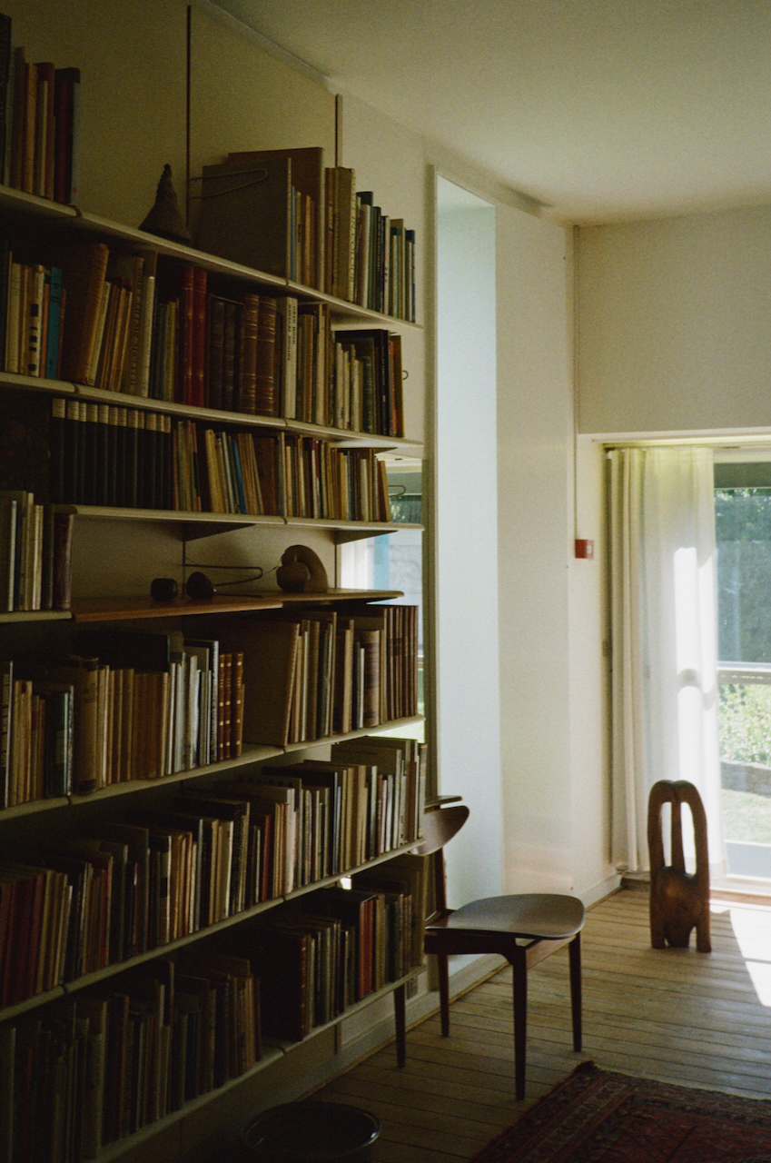 A room with a bookshelf filled with books, a window, and a chair