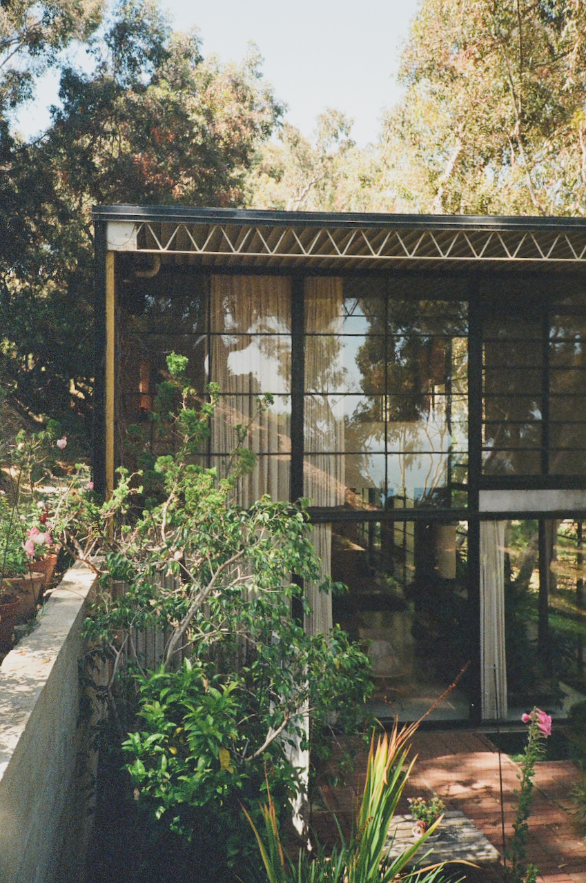 A modern house with a large glass window, surrounded by a well-maintained garden