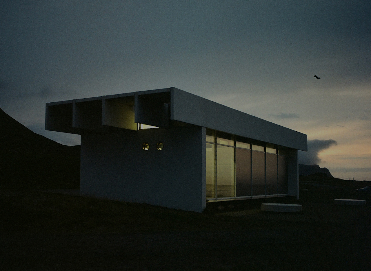 Modern building with flat roof, set against a dark sky