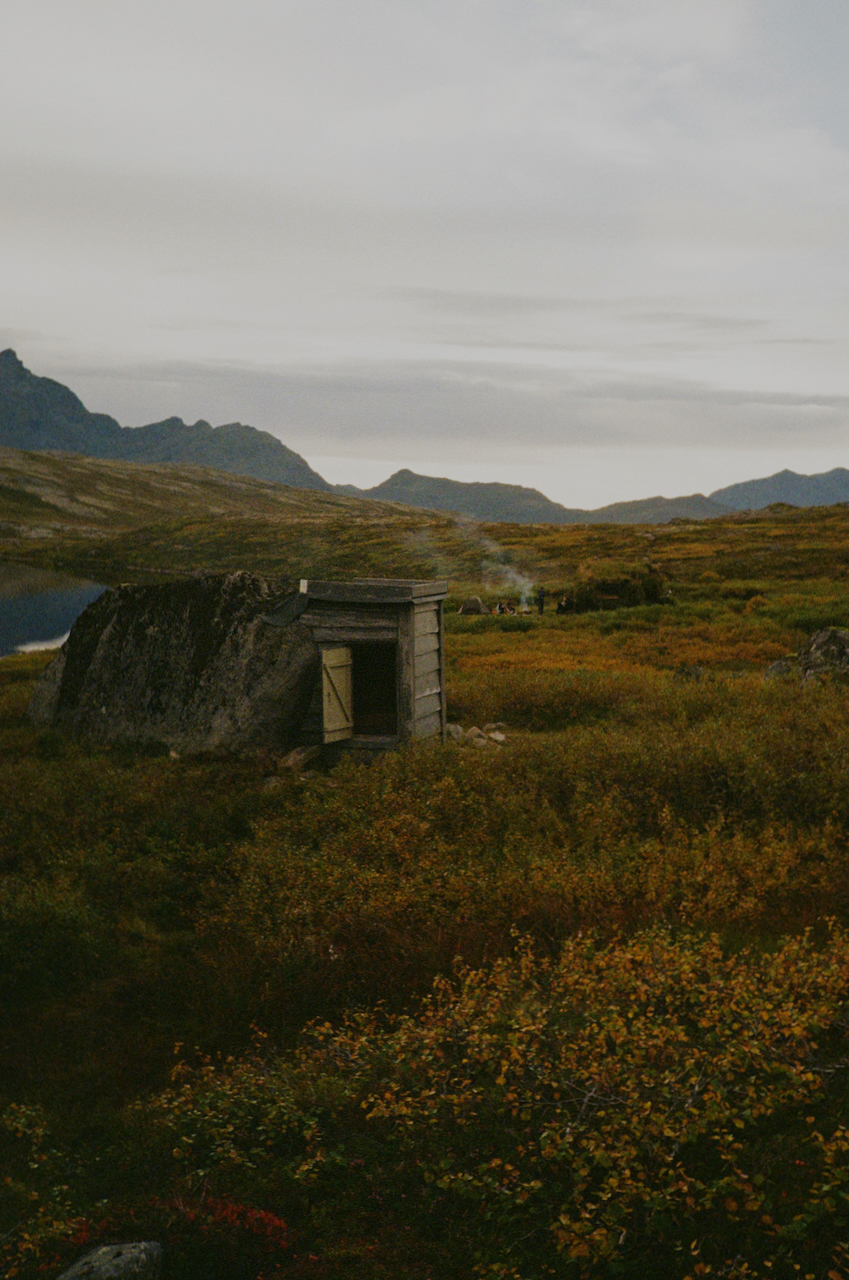 A remote mountainous area with a small building and a dirt road