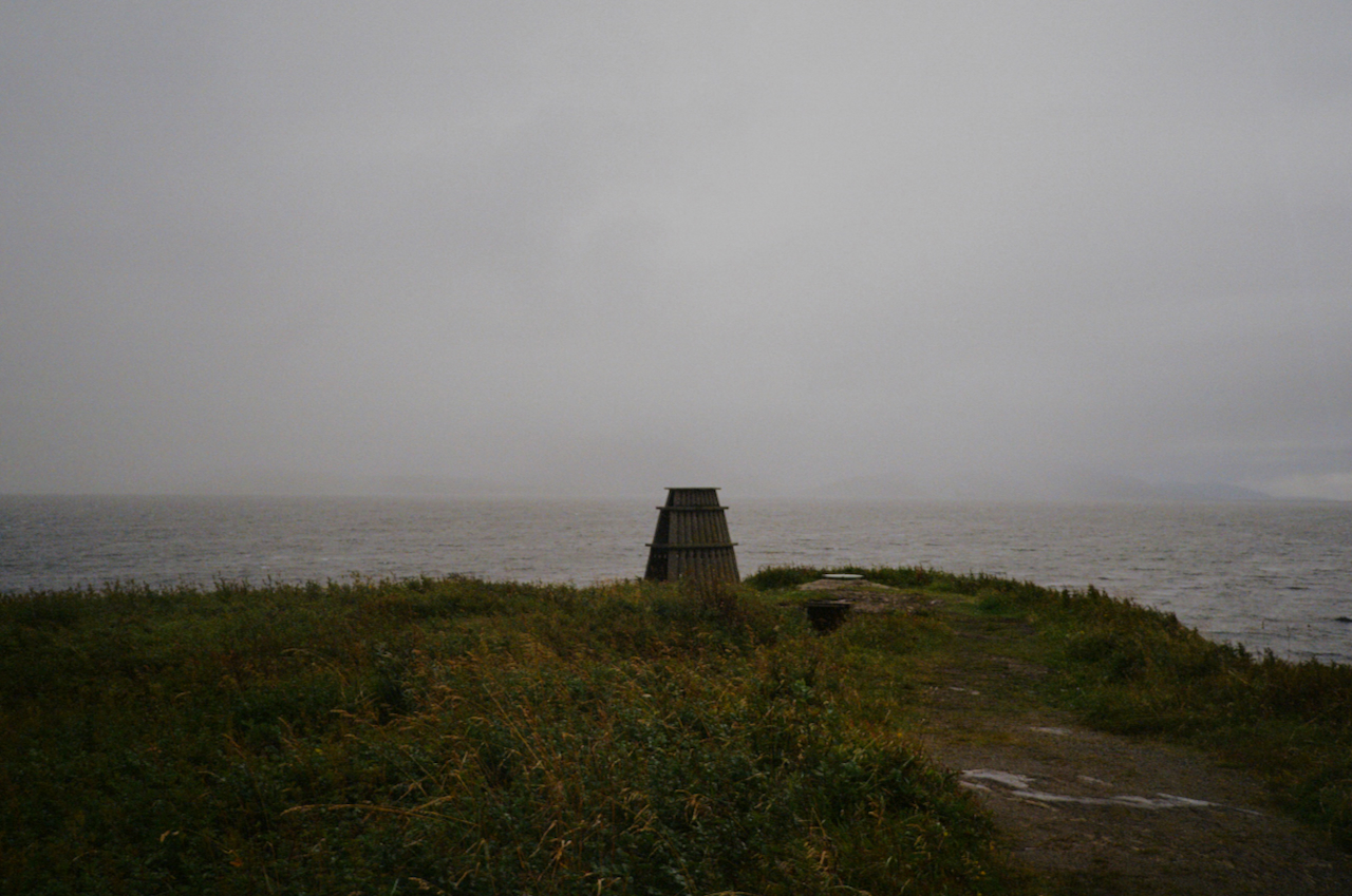 A lighthouse on a rocky shore in the rain